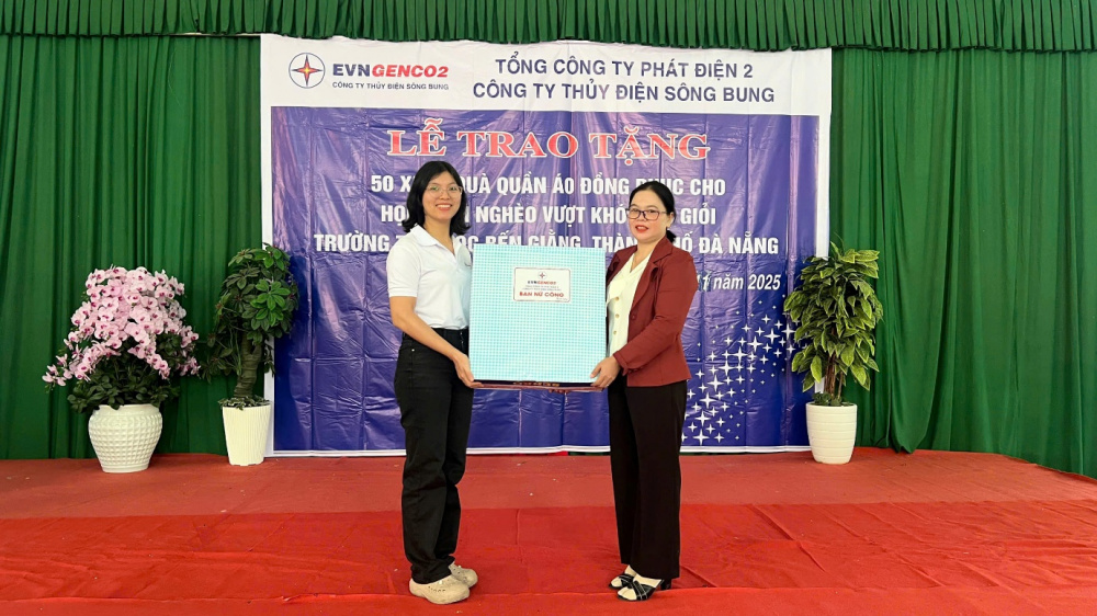 Bà Nguyễn Nho Bích Trâm – Trưởng Ban Nữ công Công ty Thủy điện Sông Bung (bìa trái) – trao tặng quà của Ban Nữ công cho cô Kring Lưu – Hiệu trưởng Trường Tiểu học Bến Giằng (bìa phải), đại diện lãnh đạo nhà trường.