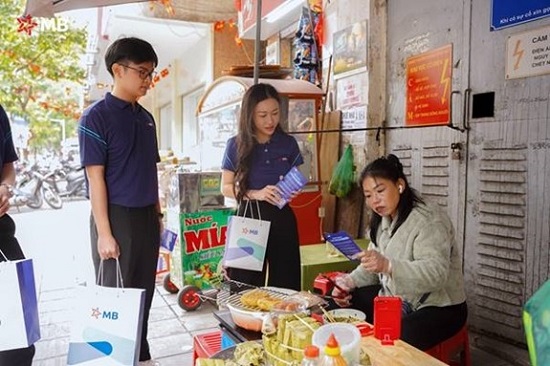 Nhân viên ngân hàng MB hướng dẫn tiểu thương chợ Hôm chuyển đổi số. Ảnh: MB