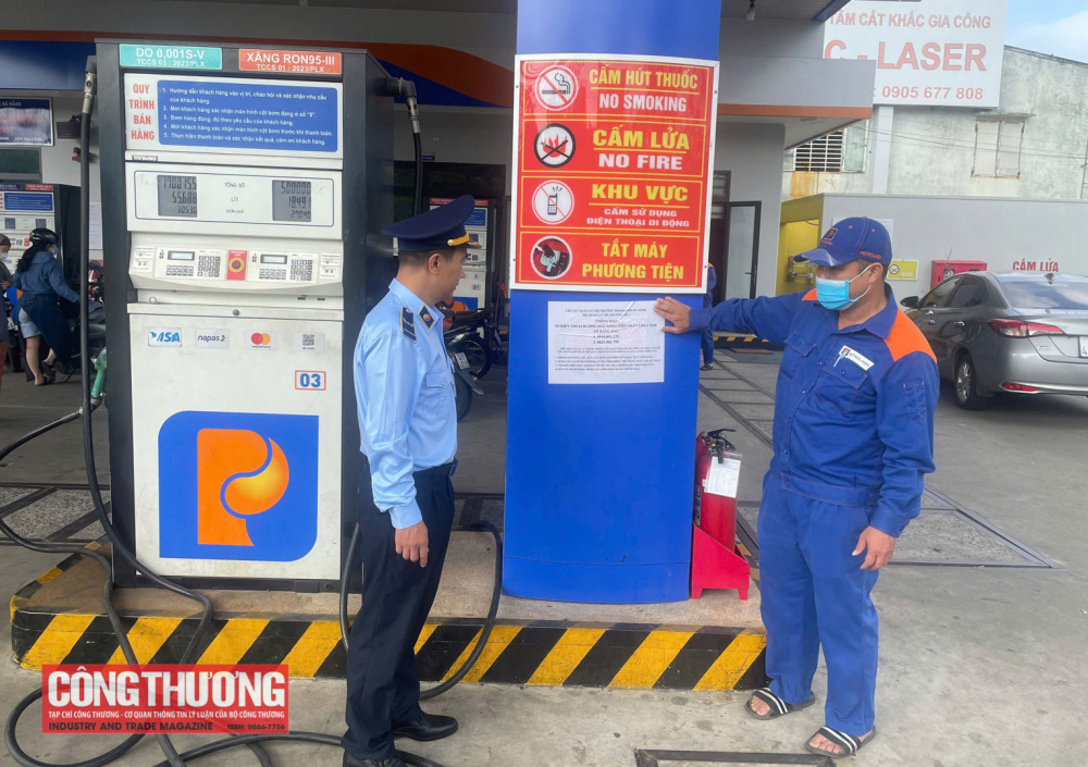 Cán bộ Chi cục Quản lý thị trường thành phố triển khai dán thông báo số điện thoại đường dây nóng tại toàn bộ cửa hàng kinh doanh xăng dầu trên địa bàn