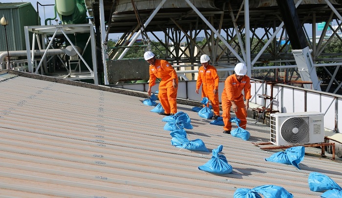 Các công nhân dùng bao cát để gia cố chống tốc mái tôn tại Nhiệt điện Bà Rịa